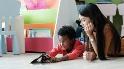 Young asian woman teacher and African boy in kindergarten classroom, preschool education concept